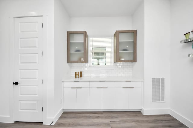 bar area with backsplash, wood finished floors, and baseboards