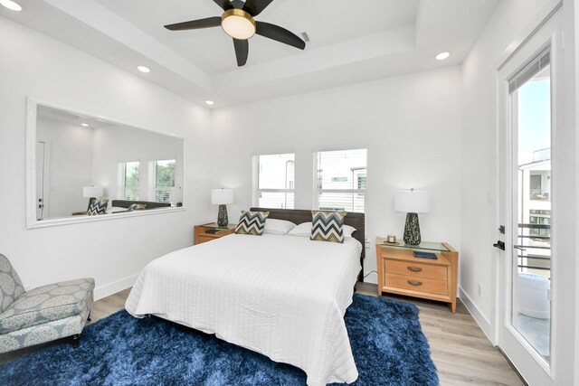 bedroom featuring recessed lighting, wood finished floors, a raised ceiling, a ceiling fan, and baseboards