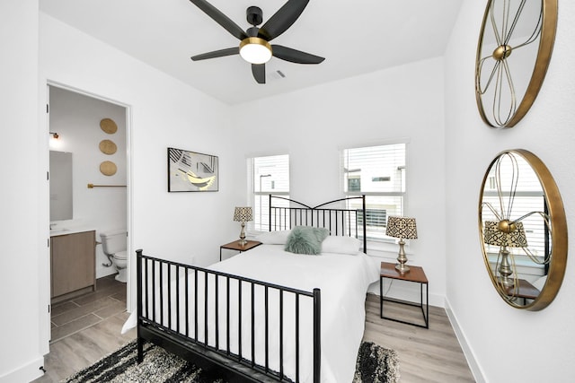 bedroom featuring light wood finished floors, ensuite bath, and baseboards