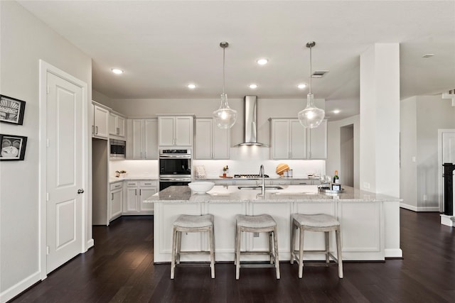 kitchen featuring wall chimney range hood, appliances with stainless steel finishes, dark wood-style flooring, white cabinets, and recessed lighting