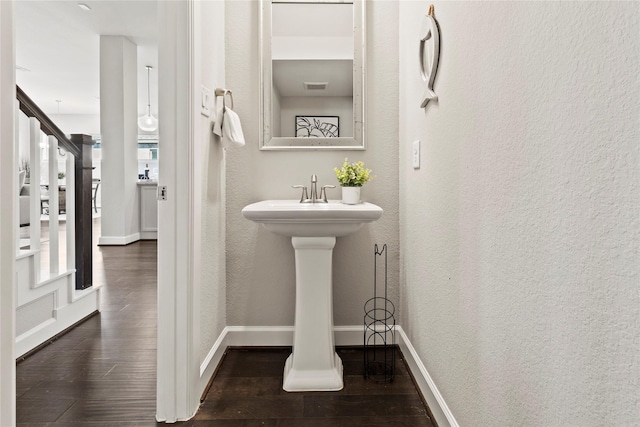 bathroom with wood finished floors, a textured wall, baseboards, and a sink