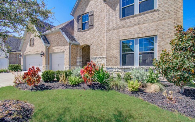 view of front of house with a garage, a front yard, brick siding, and driveway