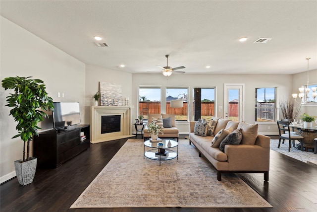 living area featuring a chandelier, a glass covered fireplace, healthy amount of natural light, dark wood-style flooring, and recessed lighting