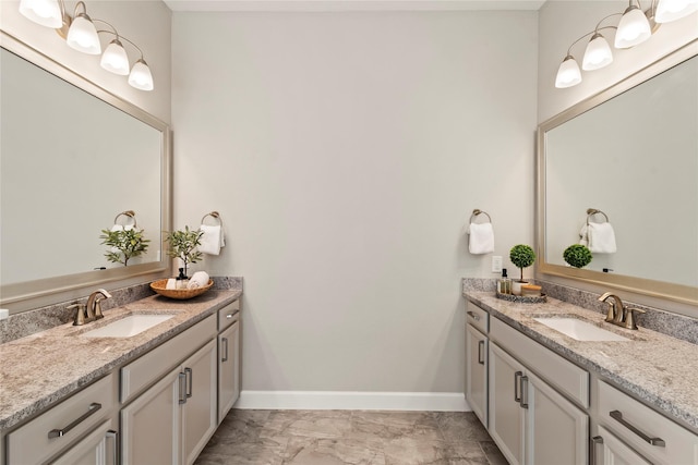 bathroom with two vanities, marble look tiles, and baseboards