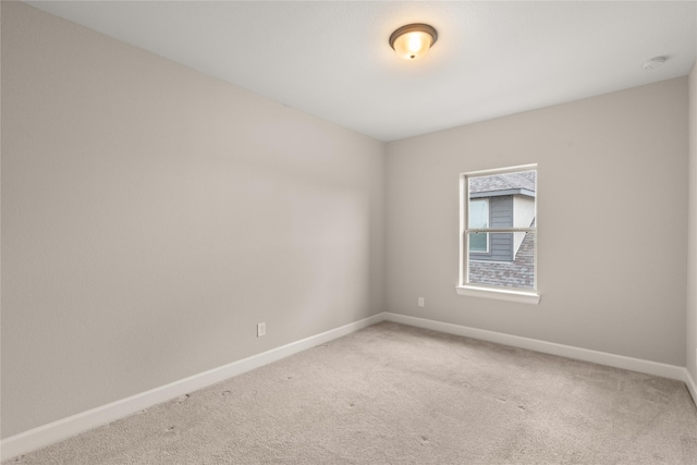 spare room with baseboards, light colored carpet, and a smoke detector