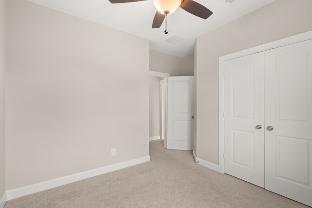 unfurnished bedroom featuring light colored carpet, baseboards, a closet, and a ceiling fan