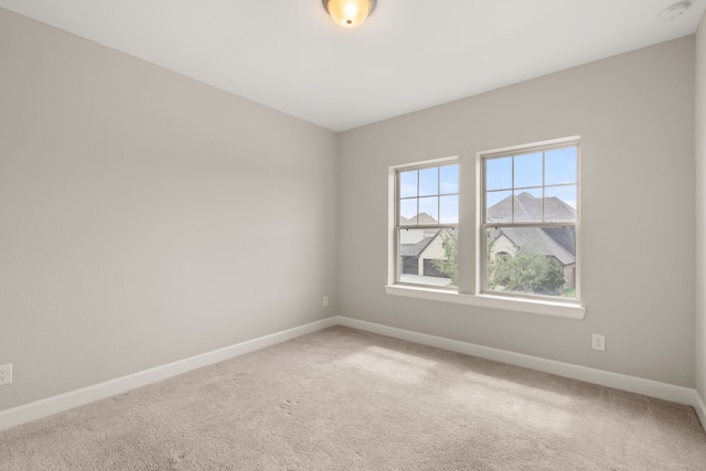 carpeted empty room featuring baseboards and a smoke detector