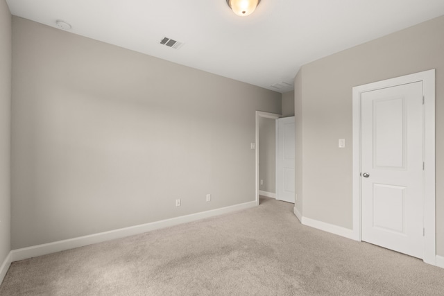 unfurnished room with light carpet, baseboards, and a smoke detector