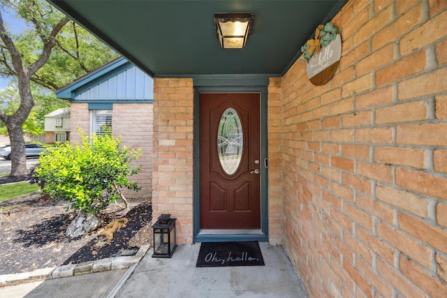 doorway to property with brick siding and board and batten siding