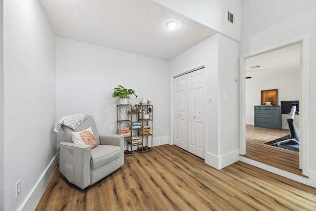 living area featuring wood finished floors, baseboards, and a textured ceiling