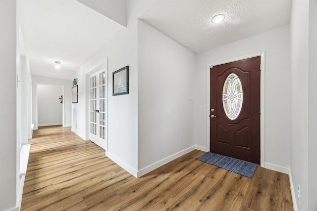 entryway with wood finished floors, baseboards, and a textured ceiling