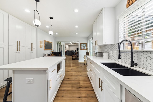 kitchen with a sink, backsplash, recessed lighting, wood finished floors, and white cabinetry