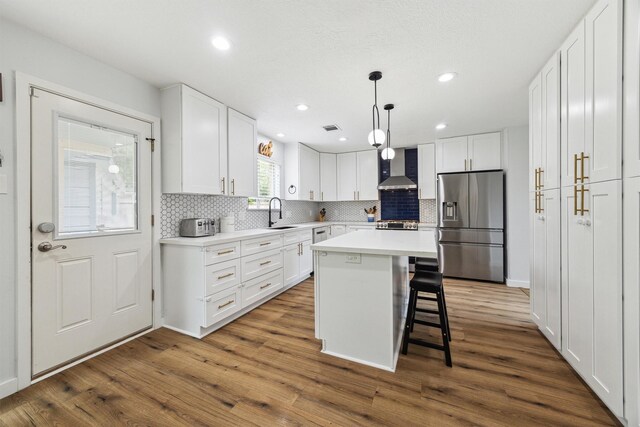 kitchen featuring stainless steel appliances, wall chimney range hood, backsplash, white cabinets, and dark wood-style floors