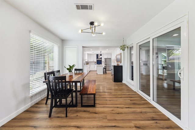 dining room with a chandelier, wood finished floors, and baseboards