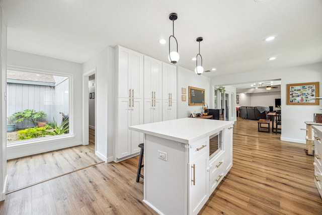kitchen featuring white cabinets, light wood-style flooring, decorative light fixtures, light countertops, and recessed lighting