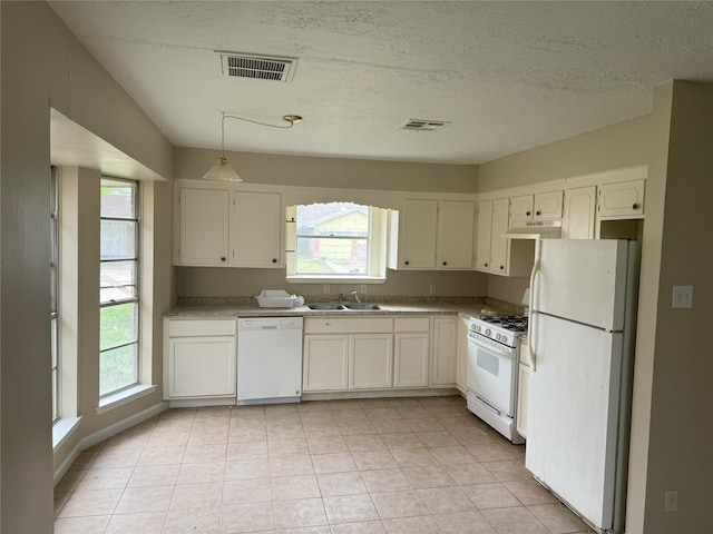 kitchen with white appliances, a sink, under cabinet range hood, healthy amount of natural light, and a textured ceiling