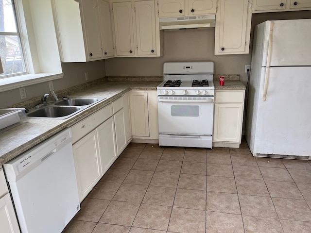 kitchen featuring white appliances, under cabinet range hood, a sink, light tile patterned flooring, and light countertops