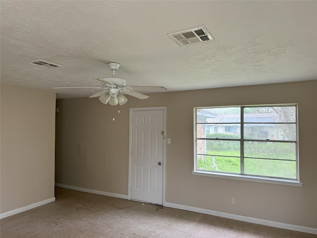 empty room with baseboards, a textured ceiling, a ceiling fan, and tile patterned flooring