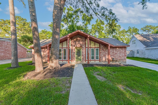 mid-century inspired home with brick siding and a front yard