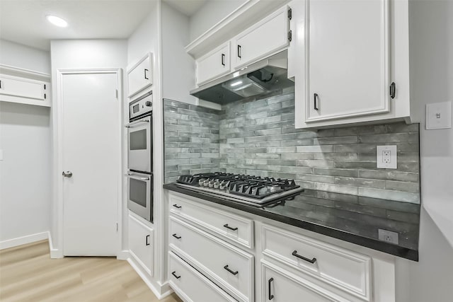kitchen with dark countertops, stainless steel appliances, light wood-type flooring, and white cabinets