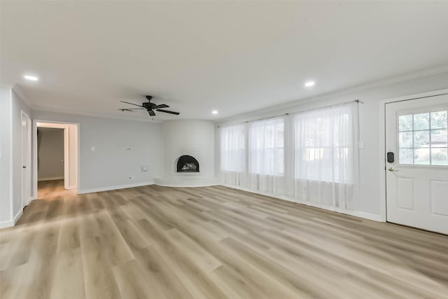 unfurnished living room with crown molding, a brick fireplace, ceiling fan, recessed lighting, and light wood-type flooring