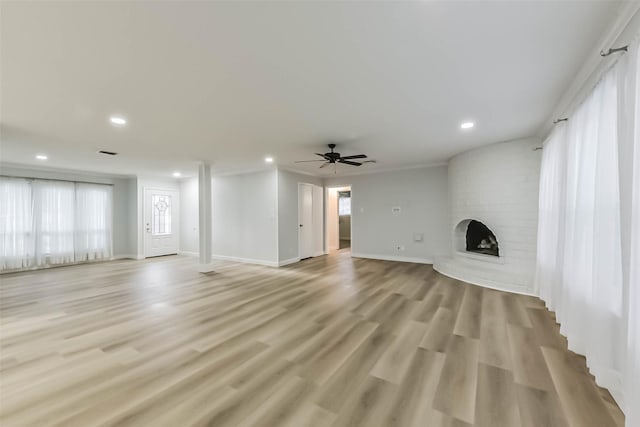 unfurnished living room featuring a brick fireplace, recessed lighting, baseboards, light wood-style flooring, and a ceiling fan