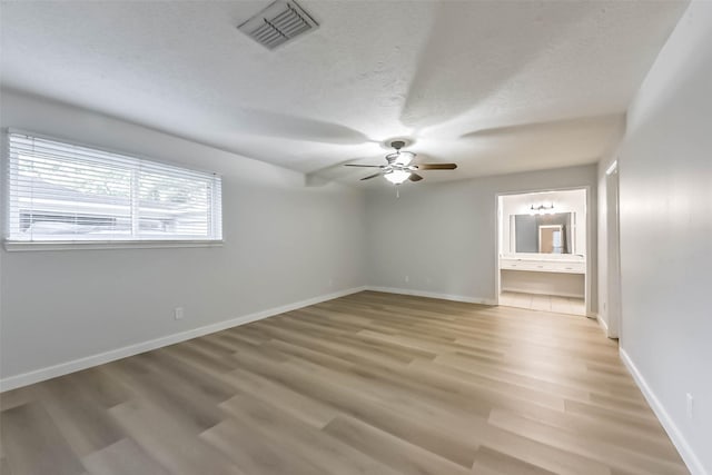empty room with ceiling fan, baseboards, light wood-style floors, and a textured ceiling