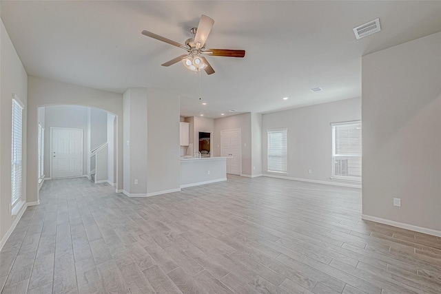 10256 Badger Run Ln, Magnolia, TX 77354 - unfurnished living room featuring arched walkways, light wood-type flooring, baseboards, a ceiling fan, and recessed lighting