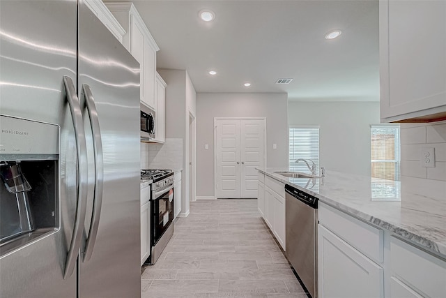 10256 Badger Run Ln, Magnolia, TX 77354 - kitchen with stainless steel appliances, a sink, tasteful backsplash, white cabinetry, and light stone counters