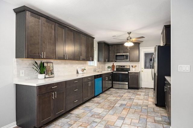 kitchen with stainless steel appliances, a sink, decorative backsplash, ceiling fan, and dark brown cabinets
