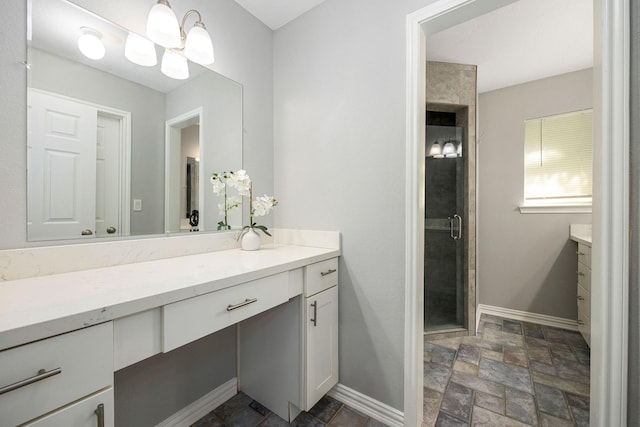 full bath featuring vanity, baseboards, stone tile floors, and a shower stall