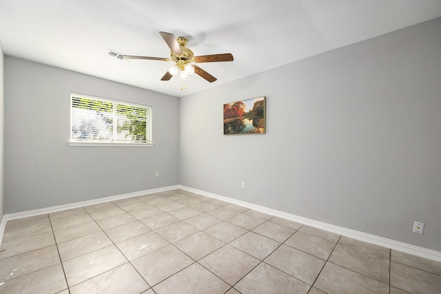 empty room featuring a ceiling fan, light tile patterned flooring, and baseboards