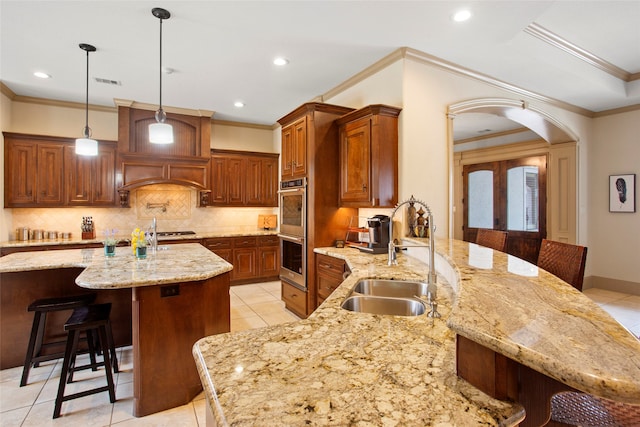 39 New Oak Trl, Humble, TX 77346 - kitchen with a sink, stainless steel appliances, a kitchen bar, arched walkways, and ornamental molding