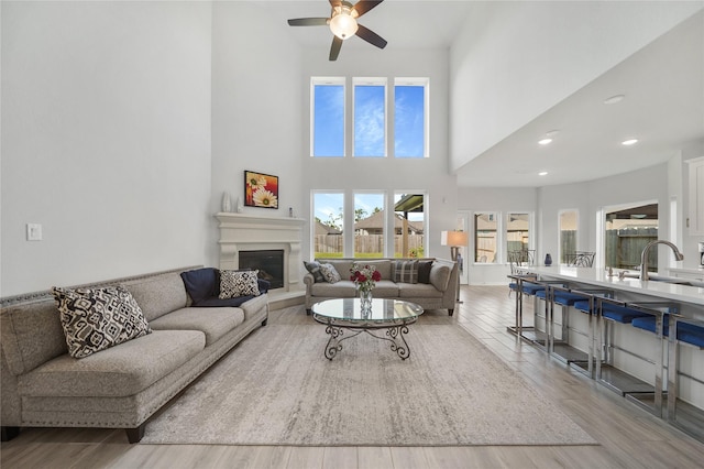 1711 Country Air Ln, Missouri City, TX 77459 - living area with ceiling fan, a glass covered fireplace, a towering ceiling, wood finished floors, and recessed lighting