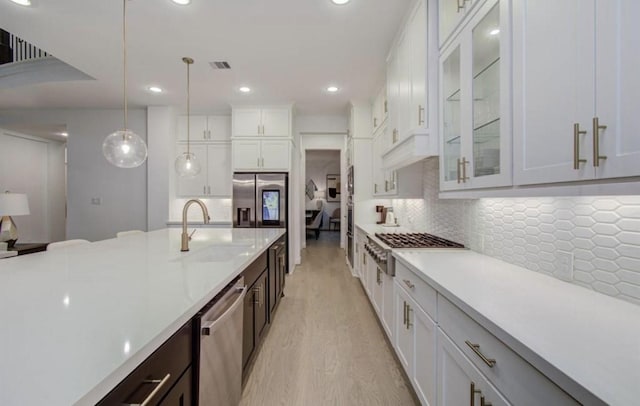 8911 Orchard Cv, Missouri City, TX 77459 - kitchen with stainless steel appliances, a sink, light countertops, light wood finished floors, and white cabinetry