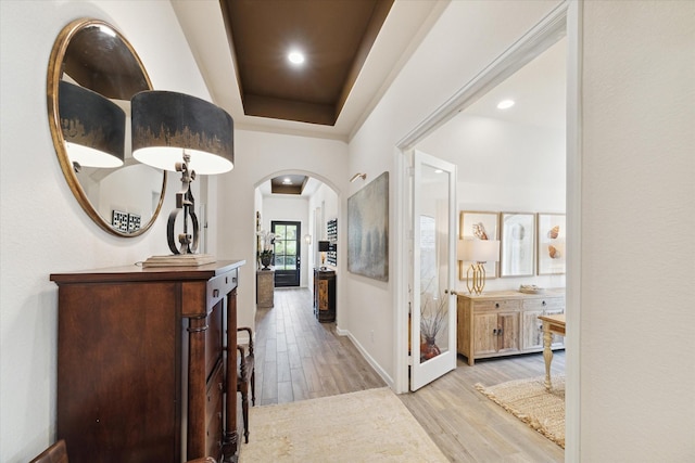7918 Silver Grove Dr, Magnolia, TX 77354 - hallway with arched walkways, light wood-style floors, a tray ceiling, recessed lighting, and baseboards