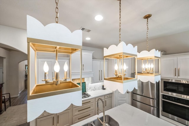 7918 Silver Grove Dr, Magnolia, TX 77354 - kitchen featuring stainless steel appliances, a sink, arched walkways, a chandelier, and hanging light fixtures