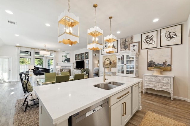 7918 Silver Grove Dr, Magnolia, TX 77354 - kitchen with a sink, stainless steel dishwasher, white cabinets, a fireplace, and wood finished floors
