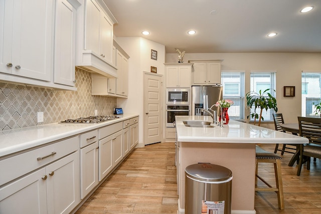 2543 Summer Peach St, Katy, TX 77494 - kitchen with appliances with stainless steel finishes, light wood-style flooring, a breakfast bar area, a sink, and a center island with sink