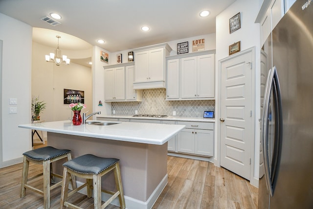 2543 Summer Peach St, Katy, TX 77494 - kitchen with stainless steel appliances, a sink, light wood-style floors, backsplash, and a kitchen breakfast bar