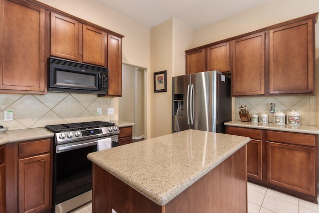 13614 Brighton Park Dr, Houston, TX 77044 - kitchen featuring appliances with stainless steel finishes, tasteful backsplash, light stone countertops, a center island, and light tile patterned floors