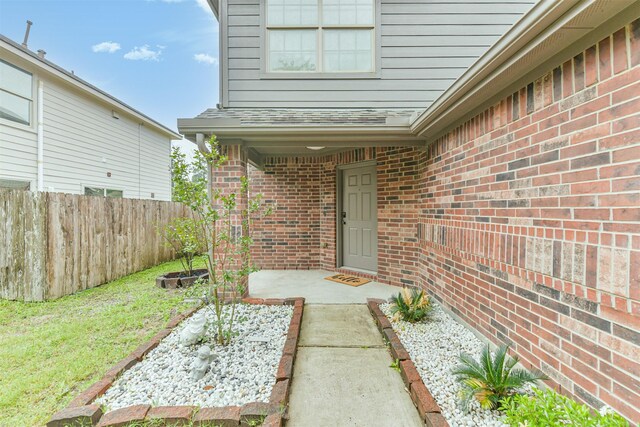 doorway to property with fence and brick siding