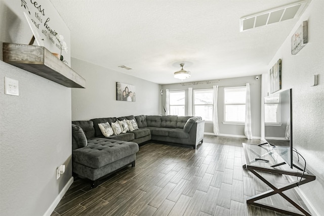 living room with baseboards, wood tiled floors, a textured ceiling, and a textured wall