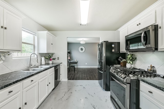 kitchen with stainless steel appliances, a sink, white cabinets, and tasteful backsplash