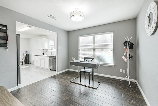 home office featuring wood finished floors, baseboards, and a sink