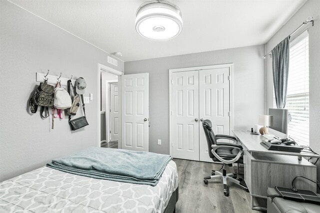 bedroom featuring wood finished floors, a desk, and a closet