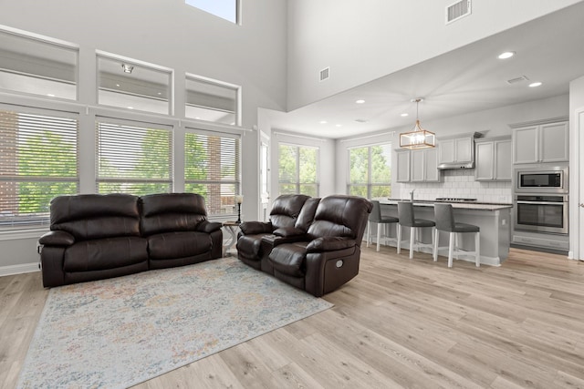 living area with light wood-style flooring and a towering ceiling