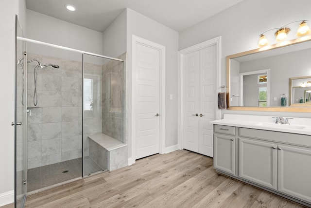 bathroom featuring a stall shower, wood finished floors, vanity, recessed lighting, and baseboards