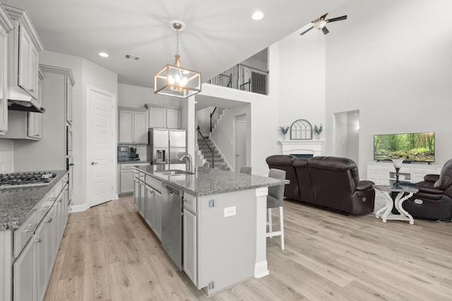 kitchen with open floor plan, stainless steel appliances, a fireplace, a sink, and a chandelier
