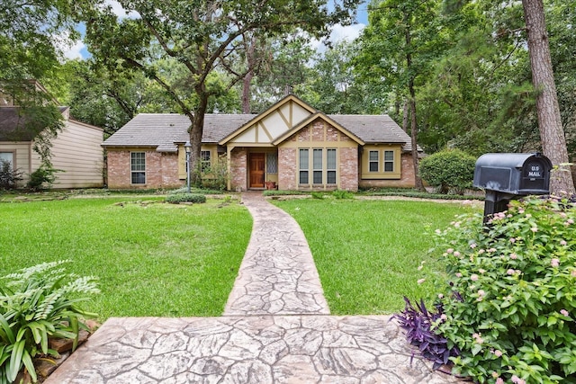 tudor home with brick siding and a front yard
